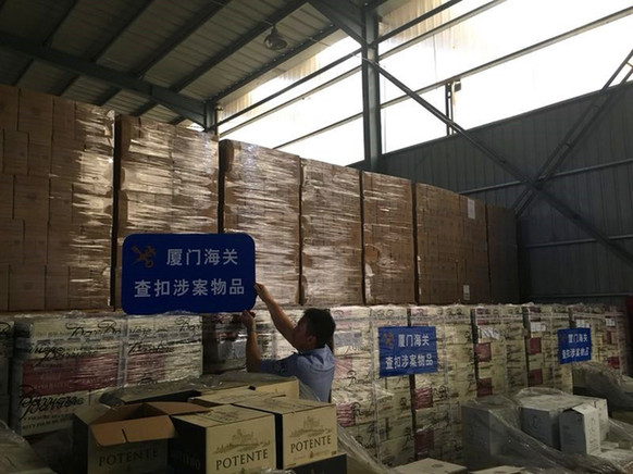 办案人员清点现场查扣的走私葡萄酒。图片来源：法制日报