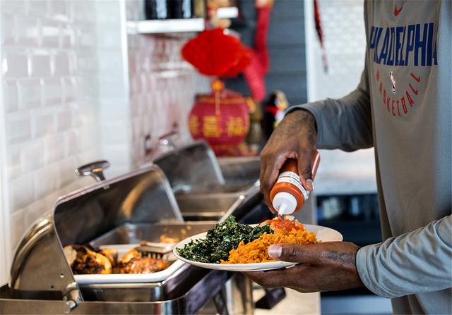 阿米尔-约翰逊在为食物装盘，他要带着这份午餐去参加球队会议