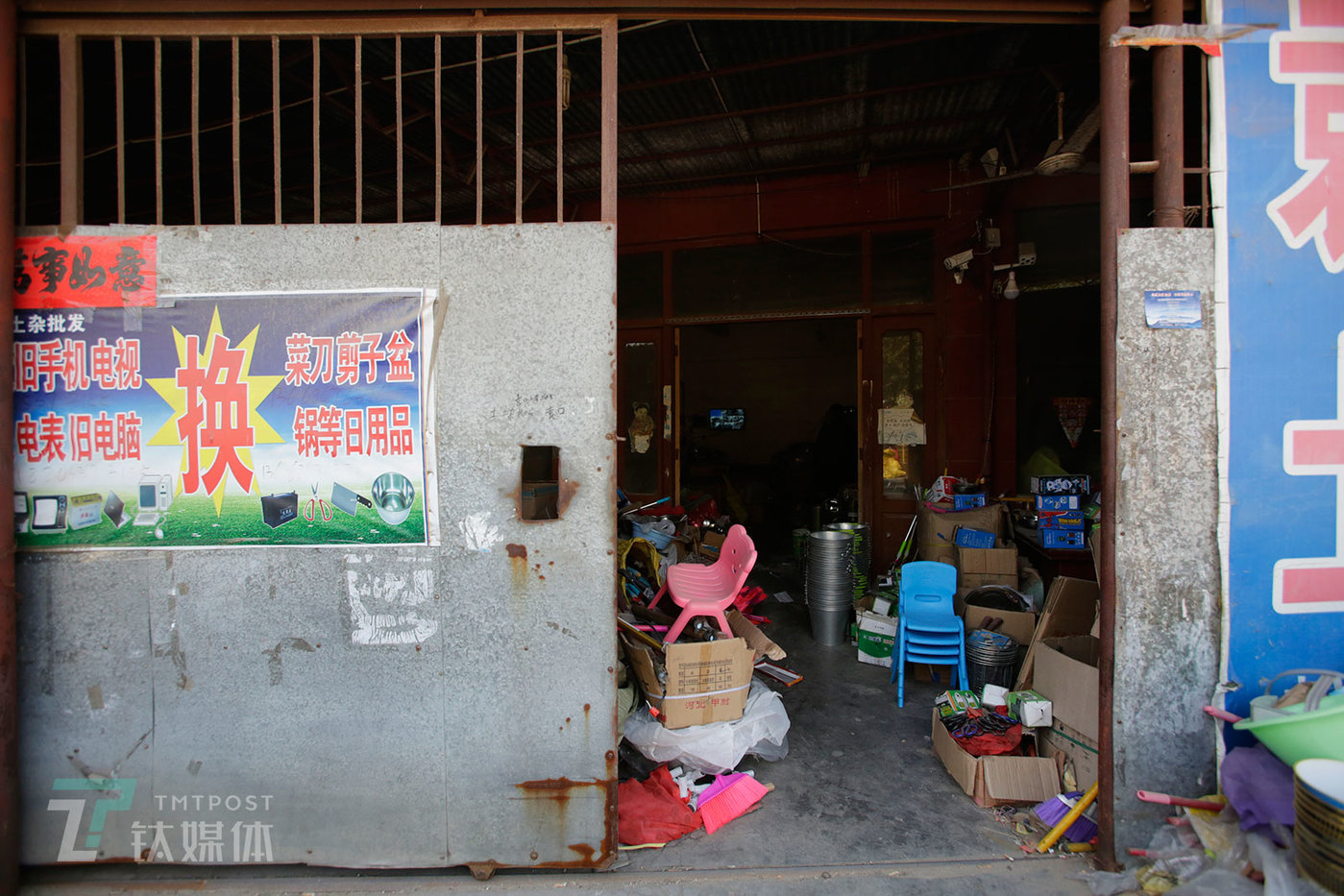2018年10月11日，山东省梁山县韩岗镇一家日杂用品批发商店，大门上贴着换旧手机电器的广告。  这家商店专门批发锅碗瓢盆等日用品，它的买家是那些开着小货车换手机的商贩：他们大批购进日杂品，然后拉着日杂品走村串乡换手机，再把换来的手机卖给梁山当地回收商。