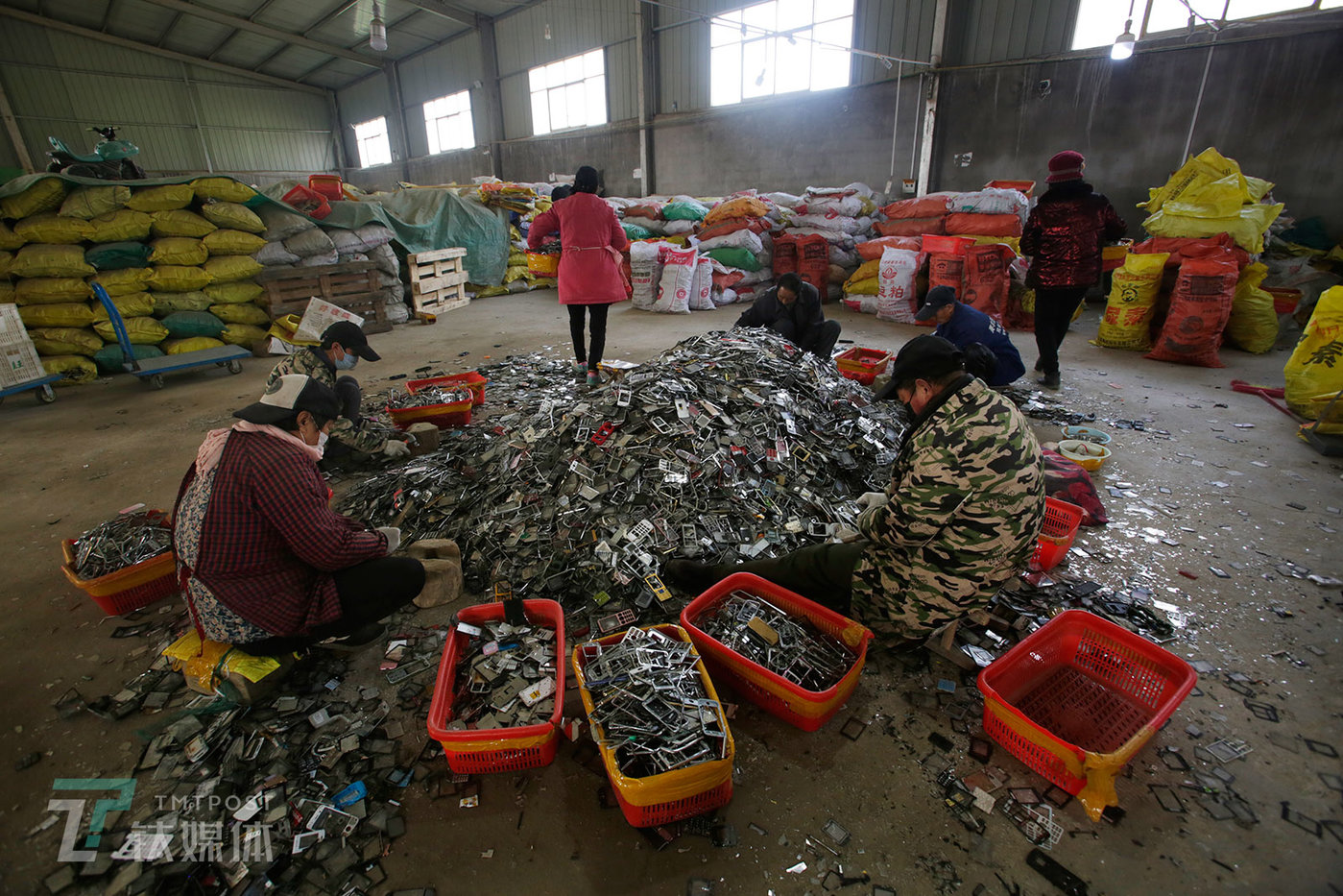 拆解厂内，几名工人在处理手机金属外壳，他们的工作是用锤子把外壳上的塑料屏保敲下来。这些金属壳会被专门的收购商买走用于提炼锌。