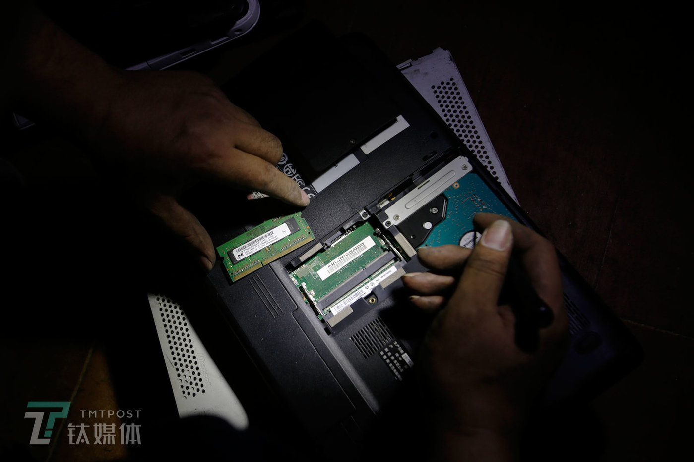 一位笔记本买家拆开一台废旧笔记本后盖检查配置。除了屏幕，内存条和硬盘的配置是决定一台废旧笔记本价格的重要因素。显然，深圳的买家对笔记等3C产品的熟悉程度和鉴别真伪的能力，远远超过全国各地涌来的卖家们。