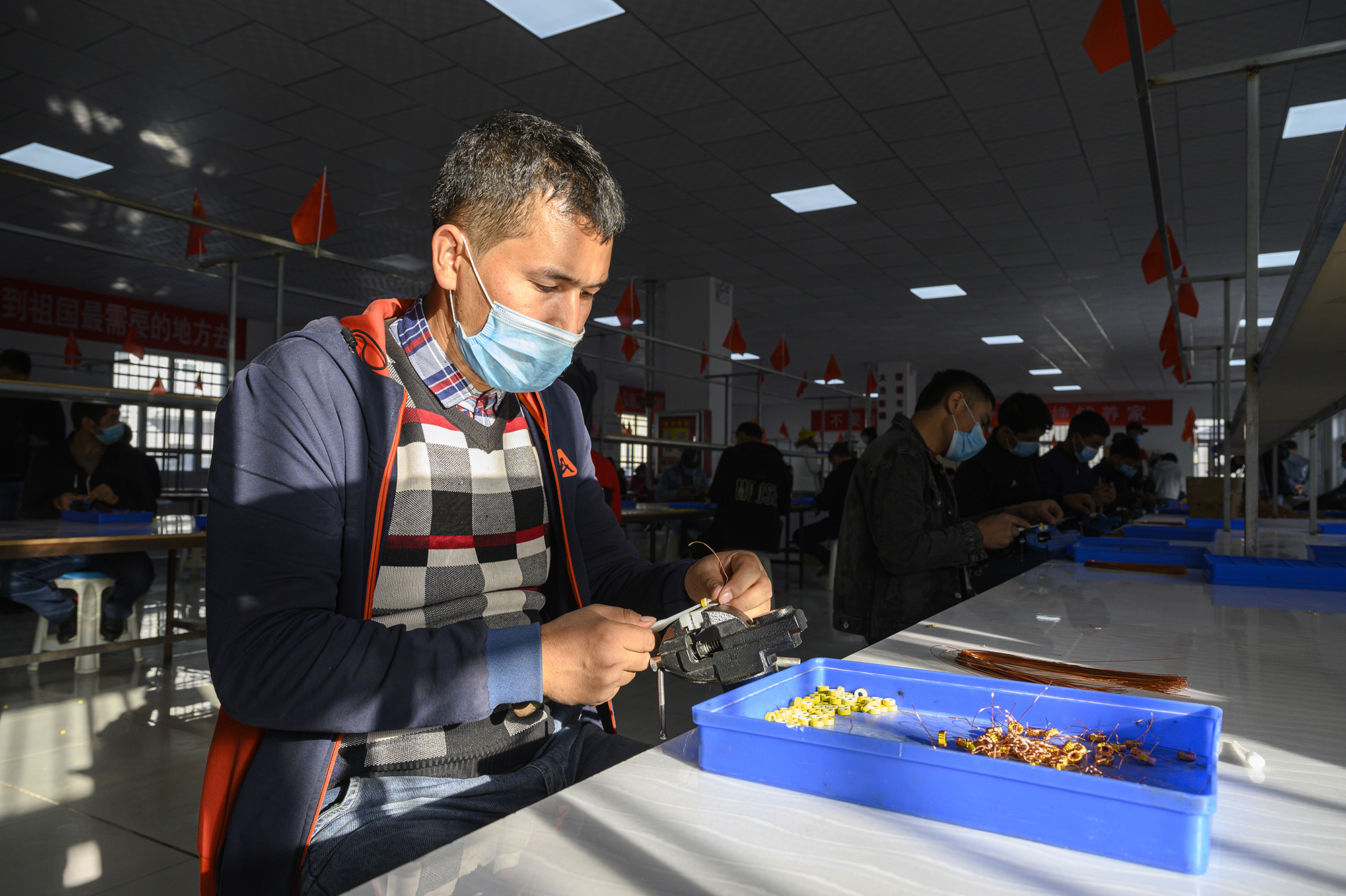 2020年10月20日，新疆克州阿克陶县巴仁乡，一位工作人员在车间里制作线圈。