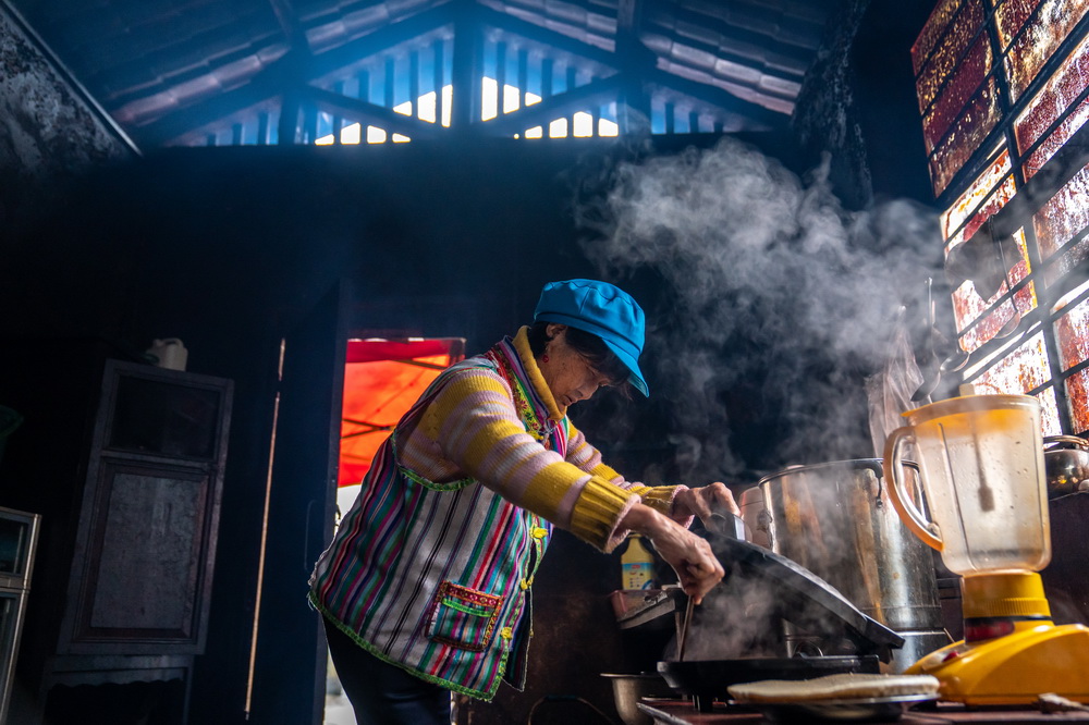 在云南省贡山独龙族怒族自治县独龙江乡孔当村,独龙族老人当那在厨房烙饼(11月1日摄)。新华社记者 胡超 摄