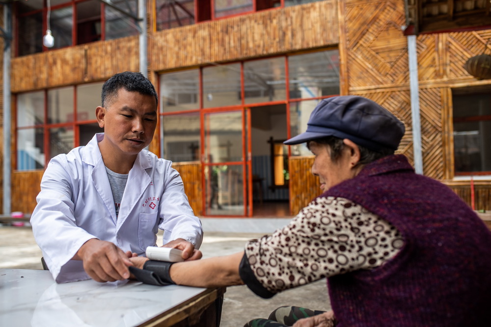 在云南省贡山独龙族怒族自治县独龙江乡巴坡村,村医孟文新给独龙族老人马桂英测量血压(10月26日摄)。新华社记者 胡超 摄